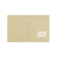 Nobodinoz Wickelunterlage Mozart in Green Tea – zusammengefaltet auf einem Holztisch mit Sicht auf das weiche Innenfutter