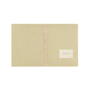 Nobodinoz Wickelunterlage Mozart in Green Tea – zusammengefaltet auf einem Holztisch mit Sicht auf das weiche Innenfutter