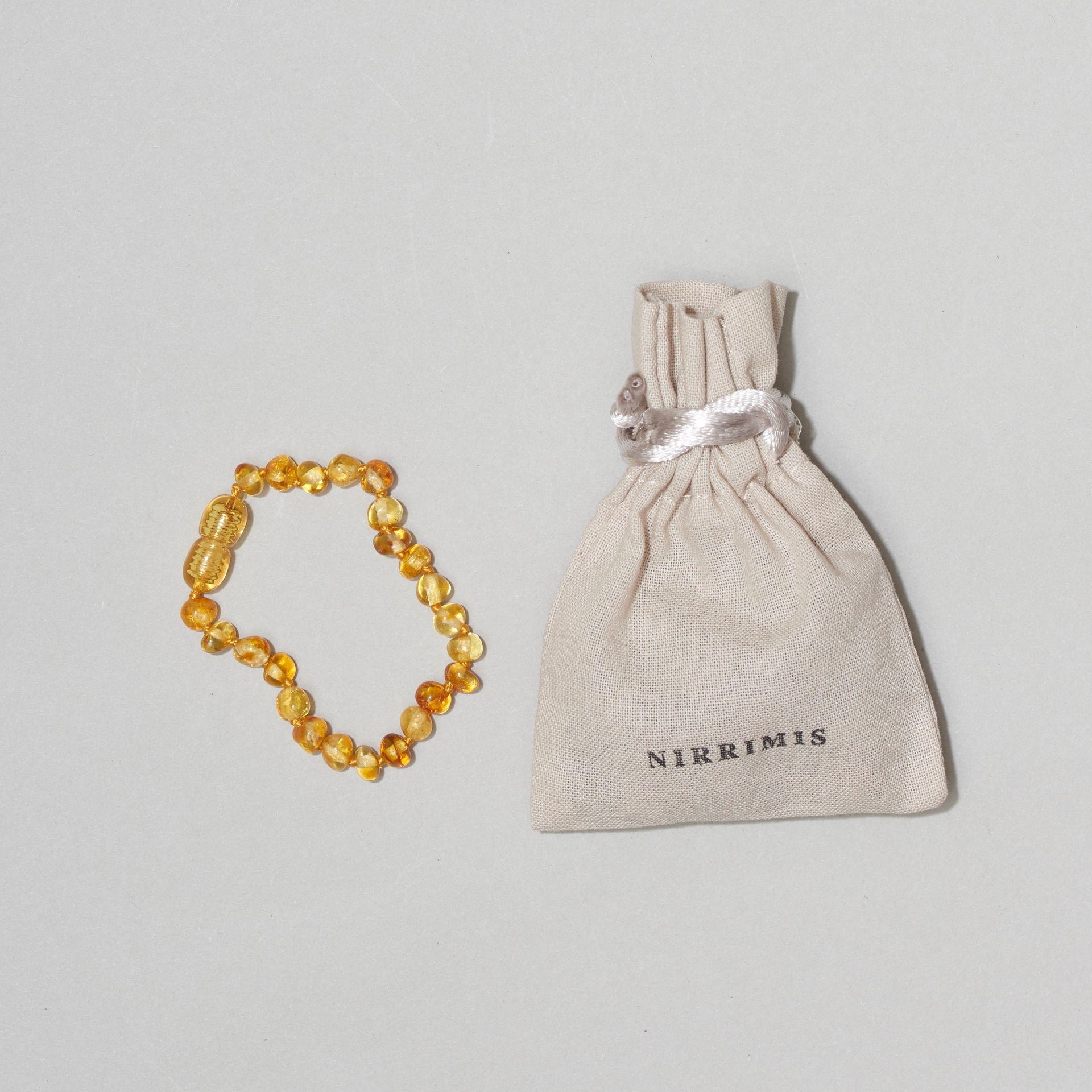 Bernstein-Armkette „Faye“ Kids von Nirrimis, 14 cm, mit Sicherheits-Pop-up-Verschluss, handgefertigt aus poliertem Honigbernstein, im Leinenbeutel.