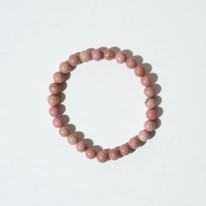 Armkette „Berry“ von Nirrimis aus rosafarbenen Rodochrosit-Perlen auf elastischem Band, flach liegend auf hellem Untergrund.