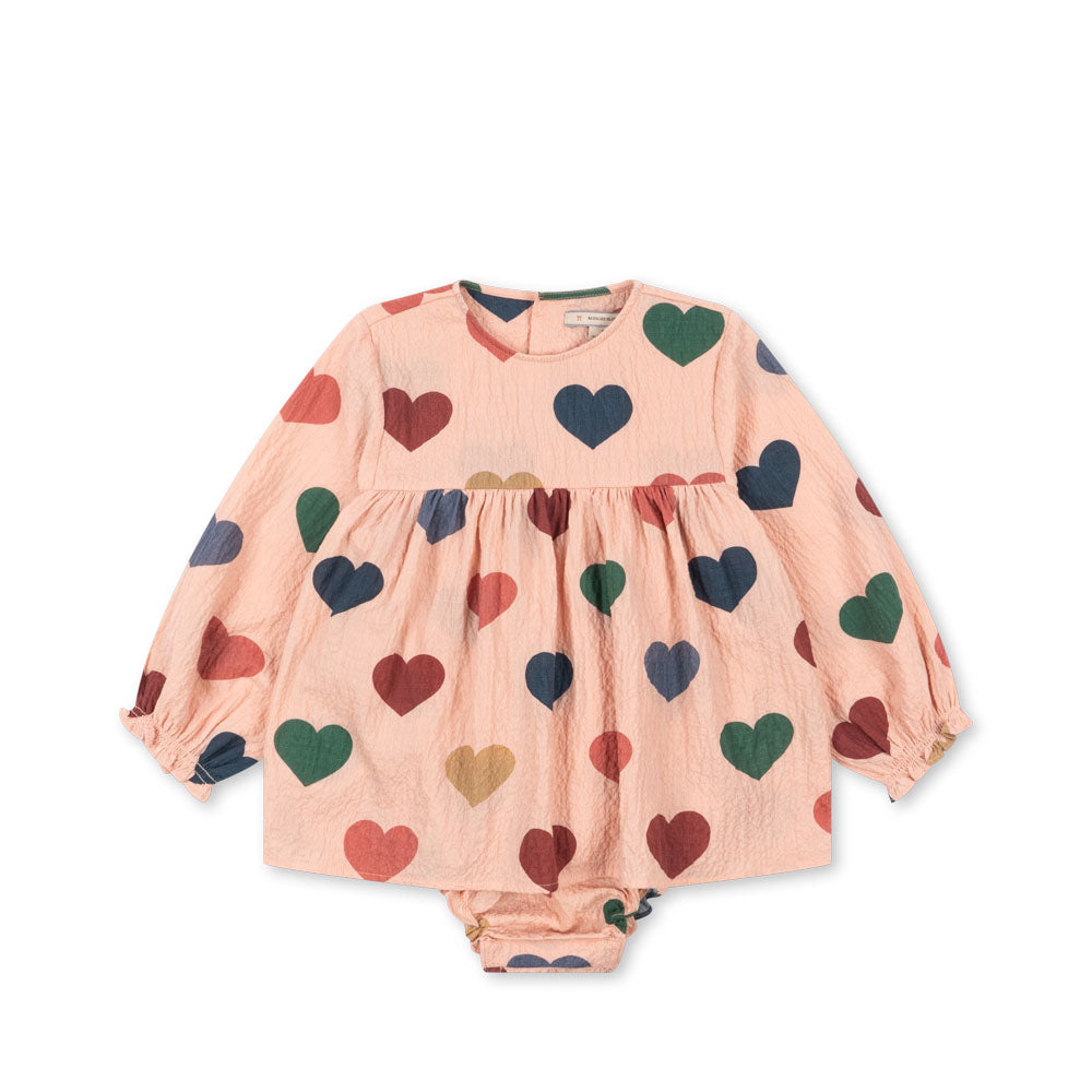 Konges Sløjd ELIN Romper aus gekräuseltem Seersucker-Stoff in Rosa mit Herzchen, GOTS-zertifizierte Bio-Baumwolle, mit Druckknöpfen und Raffungen an den Ärmeln.