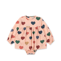 Konges Sløjd ELIN Romper aus gekräuseltem Seersucker-Stoff in Rosa mit Herzchen, GOTS-zertifizierte Bio-Baumwolle, mit Druckknöpfen und Raffungen an den Ärmeln.